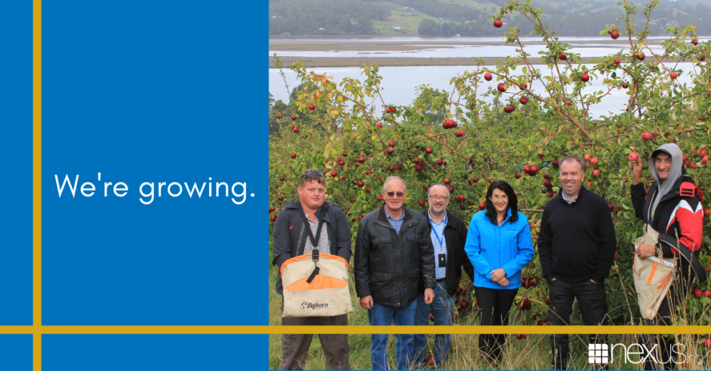 Image saying 'We're growing' with a photo of two Nexus clients, Hon Jacquie Petrusma MP, Nic Street MP, Nexus CEO Mark Jessop, and Stephen Jacques from the Huon Disability Support Network. They are standing in an orchard which is part of the new disability support in the Huon that Nexus is providing.